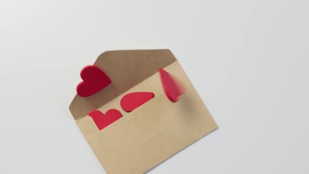 Caindo envelope de papel artesanal e muitos corações de madeira vermelha dentro saindo — Vídeo de Stock