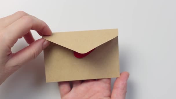 Mãos abrindo envelope de papel artesanal símbolo de forma de coração vermelho dentro, conceito de amor — Vídeo de Stock