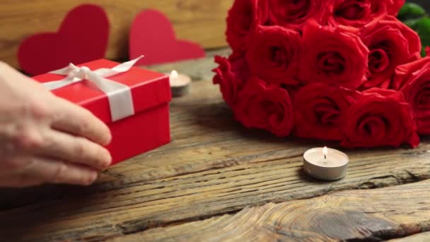 Любовь подарочная коробка кучу красных роз горящие свечи на деревянный стол День Святого Валентина — стоковое видео