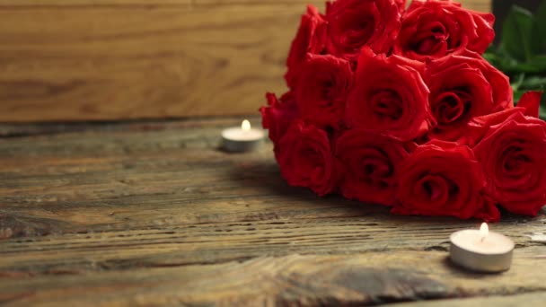 Любимый подарок коробка кучу красных роз горящие свечи деревянный стол День Святого Валентина — стоковое видео