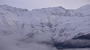 Sis, karlı dağın zirvesine doğru ilerliyor.