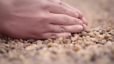 Eller kaldırır ve çakıl taşlarını bırakır.