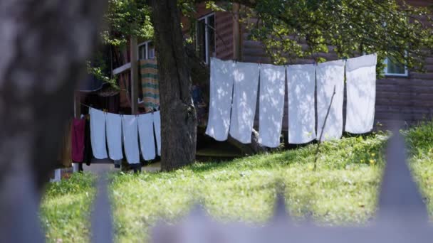 Witte lakens drogen uit in een tuin — Stockvideo