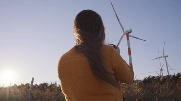 Kobieta filmująca turbiny wiatrowe o zachodzie słońca — Wideo stockowe