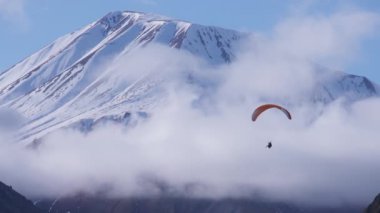 Paraglider dağ zirvelerinin yanında uçar 