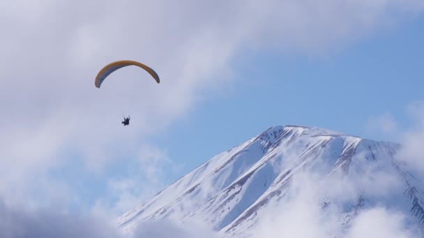 El parapente vuela por encima del pico de la montaña — Vídeo de stock
