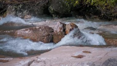 Dağ deresi kayaların arasından akıyor. Yavaş çekim. 