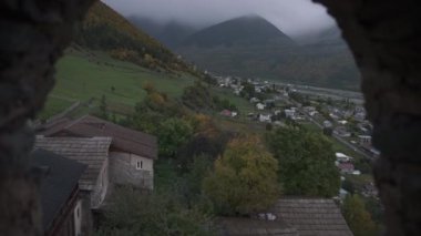 Gürcistan 'daki Svan Kulesi' nin penceresinden Kafkaslar Köyü 'ne bakıyorum. Yavaş çekim, dolly içeri. 