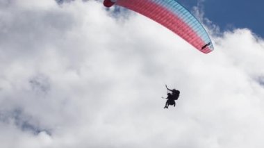 Gudauri, Gürcistan - 27 Eylül 2021: Güneş ve bulutlar altında yamaç paraşütü yapan turist ve eğitmen