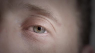 Bir erkeğin gözünü yavaşça açın. Yavaş çekim, yüzeysel alan derinliği. 