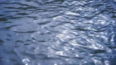 Güneş sakin mavi bir su yüzeyinden yansıyor. Su dokusunun arka planı. Yavaş çekim. 