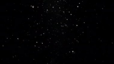 Beyaz toz parçacıkları siyah arkaplanda hızla havada süzülüyorlar. Yavaş çekim. 