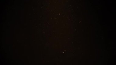 Siyah arka planda havada hızla süzülen altın renkli parçacıklar. Yavaş çekim. 