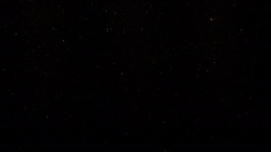 Siyah arka planda havada yüzen altın renkli toz parçacıkları. Yavaş çekim. 