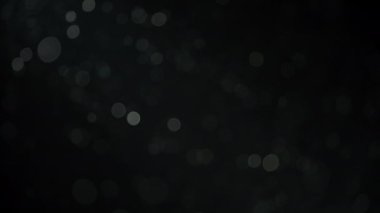 Siyah arka planda havada yüzen soyut bokeh tozu parçacıkları. Yavaş çekim. 