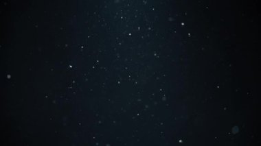 Beyaz toz parçacıkları siyah arkaplanda havada uçuşuyor. Yavaş çekim. 