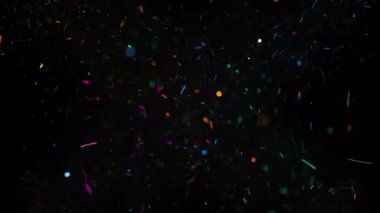 Siyah arkaplanda havada hızlı hareket eden renkli parçacıklar. 