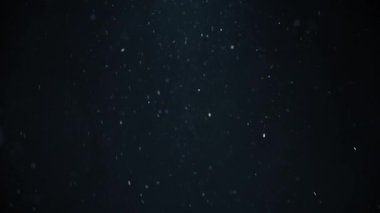 Beyaz toz parçacıkları siyah arka planda havada hızlı hareket ediyor. Yavaş çekim. 