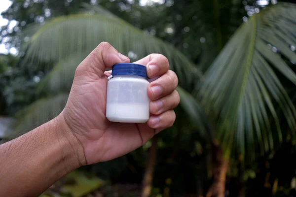 Small plastic medicine bottle in hand. Liquid product in bottle on hand.