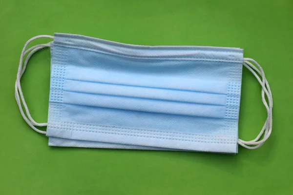 Surgical Face Mask on green background. Mask for COVID-19 pandemic situation safety. Mask use need for dust and smoke pollution. Healthcare safety in face mask.