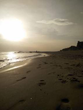 Kumsalda ayak izleri, sahilde güzel bir gün doğumu.