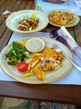 Izgara tavuk, sebzeli balık ve ahşap yüzeyde yeşil salata.