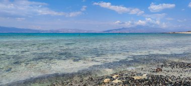 Deniz manzaralı ve arka planda dağlar.