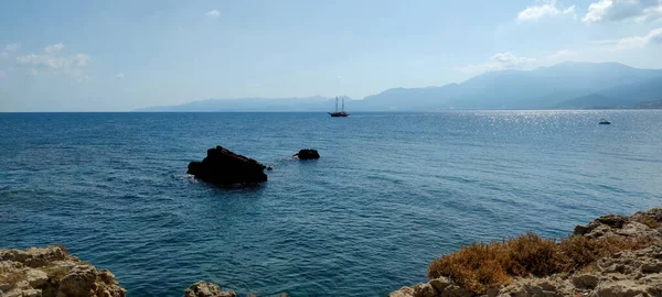 A beautiful view of a rocky coastline with the island and mountains in the background