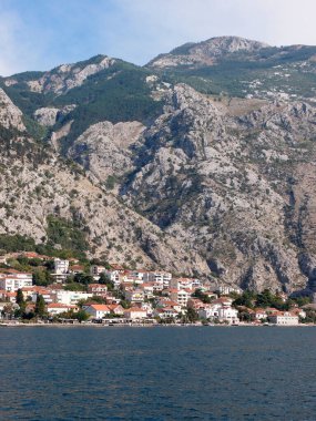Körfezdeki kıyı kasabasının güzel manzarası ve arka planında dağlar var.