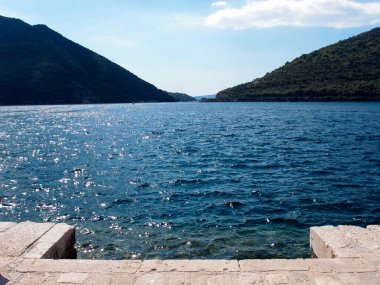 Arka planda mavi gökyüzü ve dağlar olan körfezin güzel manzarası.