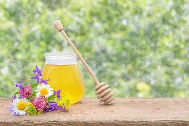 on a defocused background, a jar of fresh honey and a bouquet of wild flowers