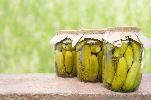 Three cans of canned cucumbers on a wooden bar