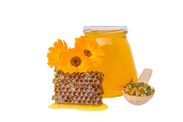 a jar with honey next to a spoon with pollen and three flowers on a white background