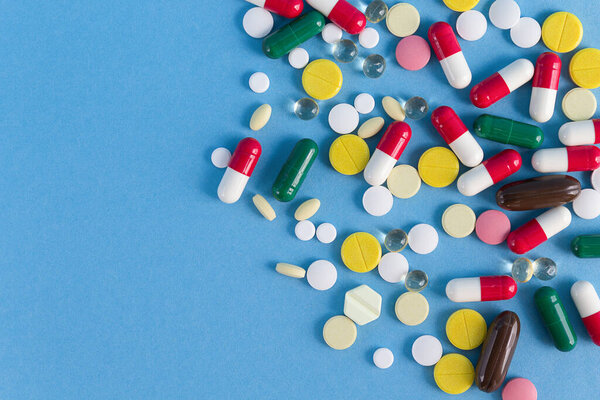 Background of multi-colored pills on a blue background