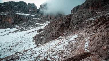 Rocky mountains in the Dolomites. Catinaccio mountain group in Italy. Via ferrata in summer in Italy. Snow in the Dolomites. Avalanche in the mountains.