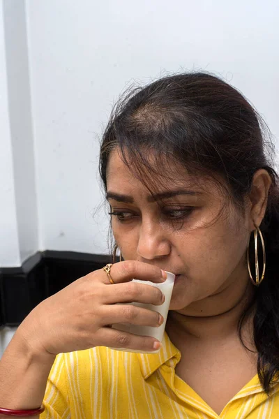 Hintli güzel bir bayan Hint sarbası içiyor ya da seçici bir odak ile ferahlatıcı bir içecek.