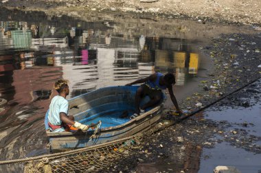 19 Kasım 2021, Kolkata, Batı Bengal, Hindistan: Teknede iki kişi Kolkata, Hindistan 'da çıplak elleriyle çöpleri temizlemeye çalışıyor.