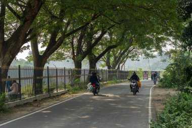 12 Aralık 2021, Narendrapur, Batı Bengal, Hindistan: Yol kenarı ağaçları ve hareket halindeki iki tekerlekli güzel bir yol.