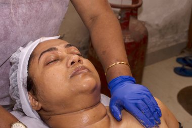 COVID yasağı sırasında genç bir kadının yüzüne maske takarak yüz prosedürü uygulaması..