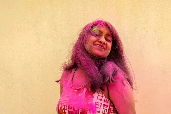 一位年轻美丽的印度女士在玩冬青粉的颜色 具有运动模糊效果和黄色背景的选择性聚焦 — 图库照片