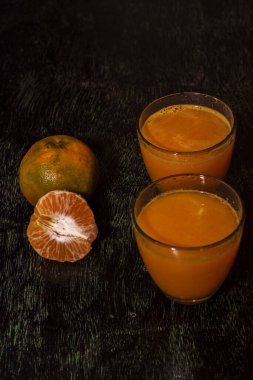 Taze portakal suyu ve koyu ahşap arka planda posası olan taze bir portakal suyu. Seçici odak.