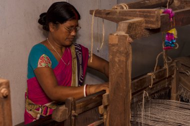 6th April, 2022, Dhupjhora, West Bengal, India: A village woman making hancrafted jute door mat useing jute rope in a hand made machine