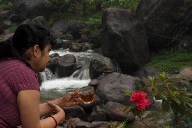 Balkonda çay içen bir kadın turist su düşüşünün tadını çıkarıyor..