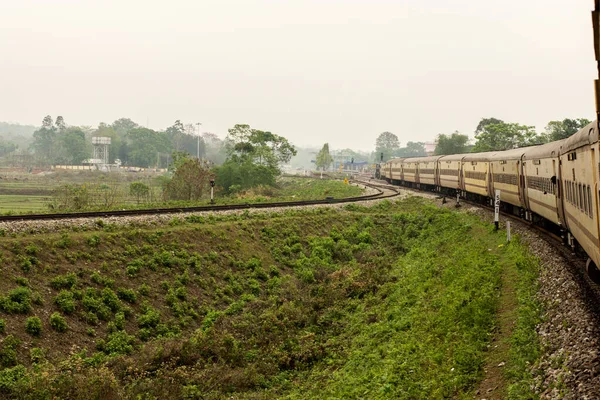 Sarı, uzun bir Hint tren yolu dizel lokomotif yolcu treni Dooars bölgesinin kırsal kesiminde seçici odaklı bir pistte..