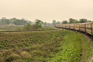 Sarı, uzun bir Hint tren yolu dizel lokomotif yolcu treni Dooars bölgesinin kırsal kesiminde seçici odaklı bir pistte..