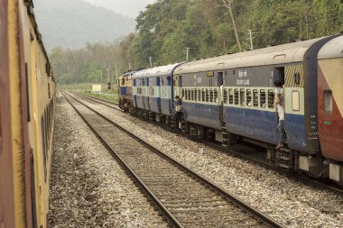 5 Nisan 2022, Shevok, Batı Bengal, Hindistan: Hint Demiryolu 'ndan iki tren Shevok İstasyonu' na vardı ve çok az yolcu raylara indi. Arkaplanda seçici odaklı dağlar.