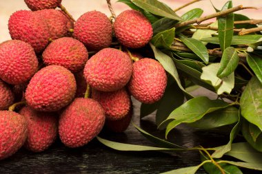 Tahta bir masanın üzerinde yaprakları olan Lychee..