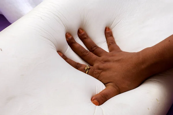 A female hand testing softness of a orthopedic memory foam pillow for comfort.
