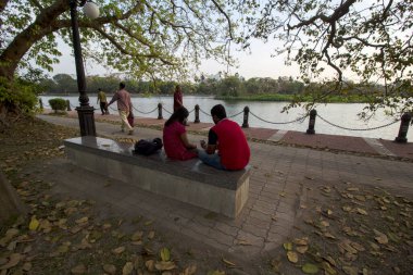 12 Mart 2022 'de, RAbindra Sarobar Gölü, Kolkata, Batı Bengal, Hindistan: Rabindra Sarobar Park formalitesi Dhakuria Gölü olarak bilinir. İki genç çift, Rabindra Sarobar gölü kenarında vakit geçiriyorlar..