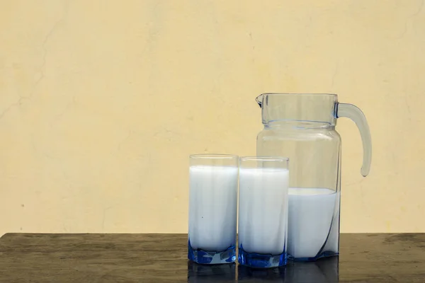 Fresh milk poured from pitcher into two glasses, healthy cow milk with copy space.